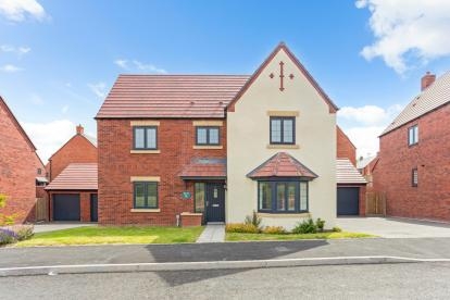 A large detached red brick and white house with bay window, small garden area at the front, driveway and detached garage