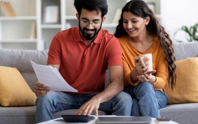 Two people sat on a sofa reading through some paperwork