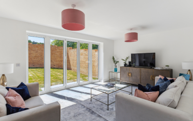 A new-build living room with white walls, patio doors leading to a sunny garden and stylish furniture inside