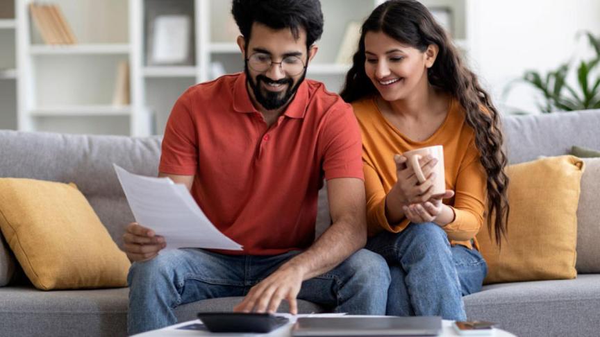 Two people sat on a sofa reading through some paperwork