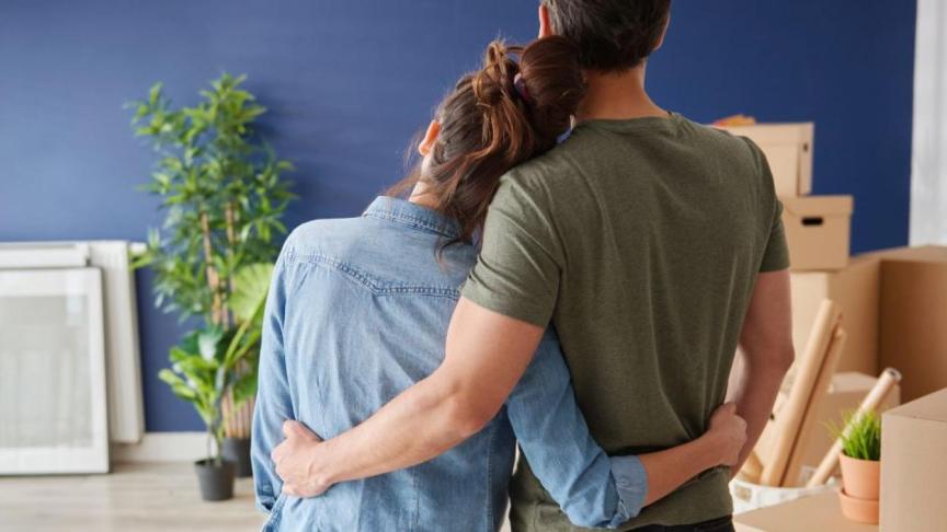 A couple embracing whilst looking towards some moving boxes