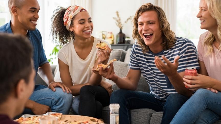 A group of friends laughing and eating pizza together