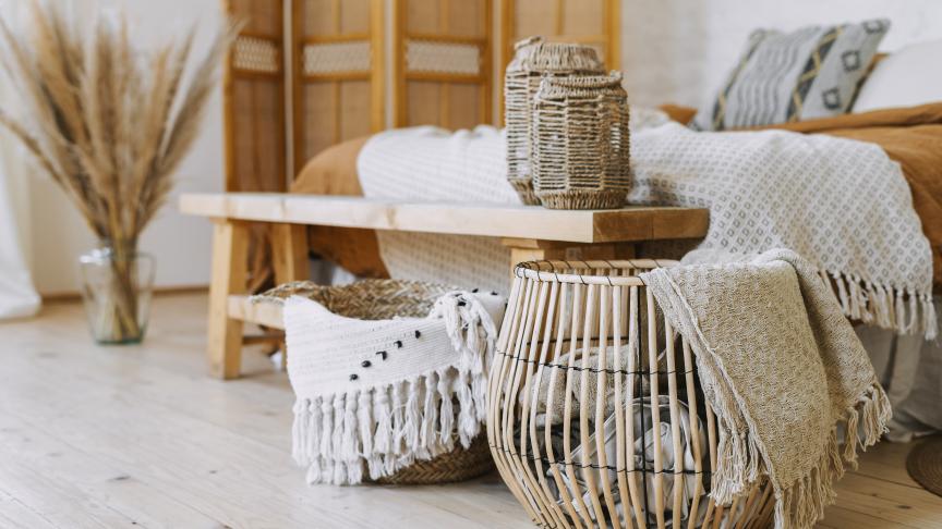 A cozy room featuring a bed, a wooden table, and a basket, creating a warm and inviting atmosphere.